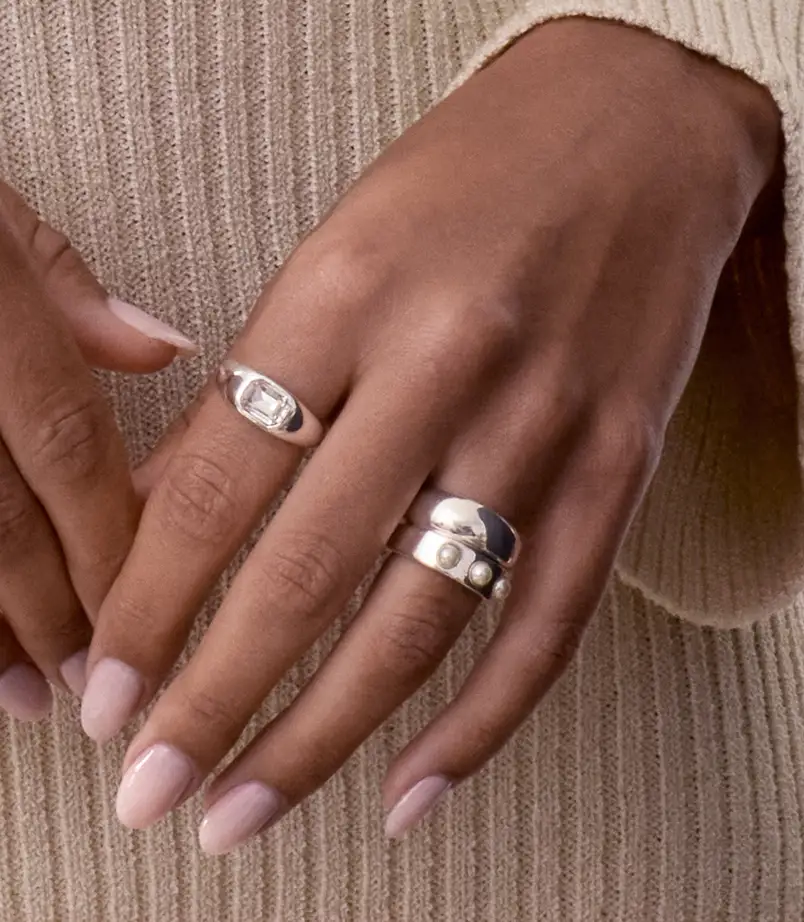 Close up of a hand wearing 2 bold silver rings